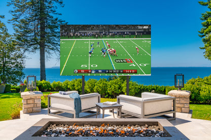 A large outdoor  TV screen mounted on a pedestal showing a football game, set in a luxurious backyard patio