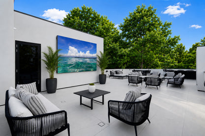 A modern outdoor patio with black woven seating and a large outdoor dvLED display.
